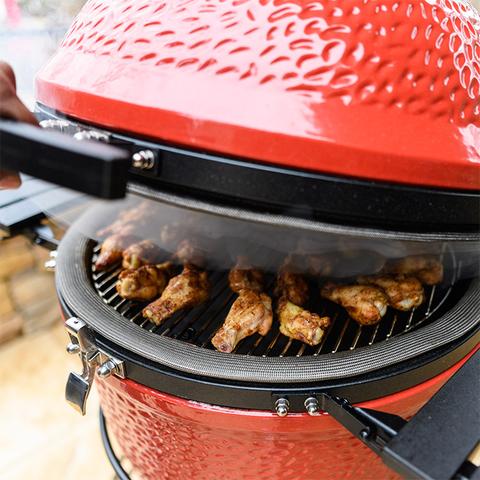 Kamado Joe ceramic Classic II Charcoal Grill, slightly open with chicken wings grilling inside